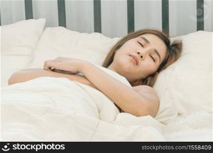 Beautiful Asian woman sleeping on the bed in the cozy white bedroom with morning light. Sleep, Relax, dream, Sick, Rest.