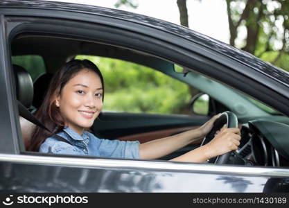 Beautiful Asian woman smiling and enjoying.driving a car on road for travel