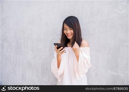 beautiful asian woman using cellphone, over concrete wall