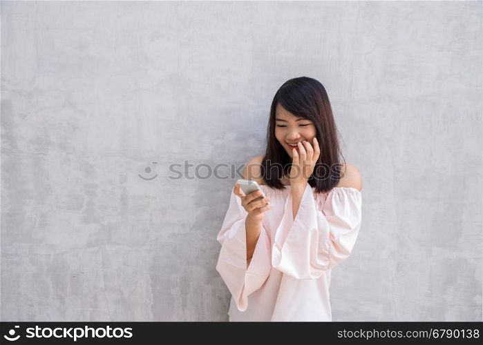 beautiful asian woman using cellphone, over concrete wall