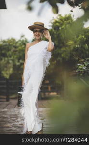 beautiful asian woman wearing white dress with straw hat toothy smiling face standing outdoor