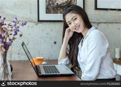 Beautiful Asian woman working with laptop and drinking coffee