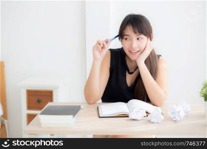 Beautiful asian woman writer smiling thinking idea writing on notebook diary with planning working on desk office, lifestyle asia girl have inspiration with success, education and business concept.
