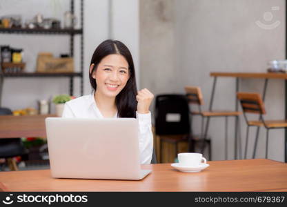 Beautiful asian young businesswoman excited and glad of success with laptop, girl using working computer coffee shop on desk, career freelance business concept.