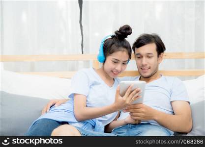 Beautiful asian young couple listening to music with tablet on bed, Love, dating,Young couple in sitting together in bed using a Tablet.
