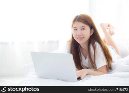 Beautiful asian young woman lying on bed using laptop at bedroom for leisure and relax, freelance with girl working notebook, communication concept.