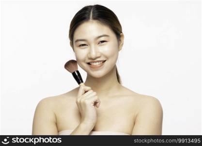 Beautiful Asian young woman smile and holding make up brush with healthy Clean and Fresh skin feeling so happiness and cheerful,Isolated on white background,Beauty Concept