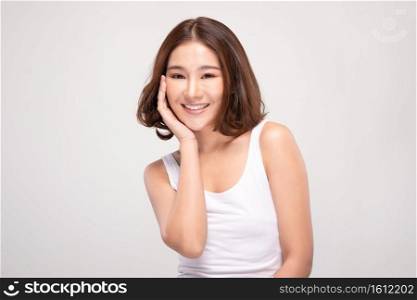 Beautiful Asian young woman touching soft cheek smile with clean and fresh skin Happiness and cheerful with positive emotional,isolated on gray background,Beauty and Cosmetics Concept