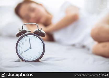 Beautiful asian young woman turn off alarm clock in good morning, wake up for sleep with closeup foreground alarm clock, relax and lifestyle concept.