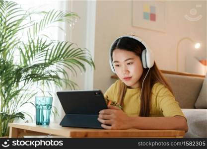 beautiful Asian young woman using a tablet and eat salad for lunch on table work at home. concept working from home