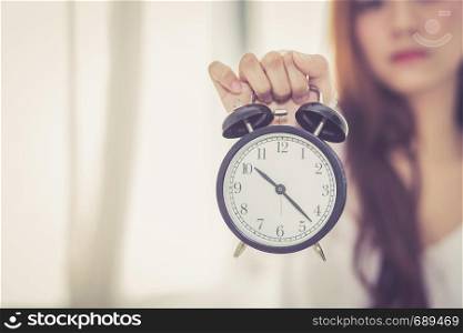 Beautiful asian young woman wake up in morning annoyed alarm clock holding hand, girl hurry wake late with appointment, lifestyle concept.