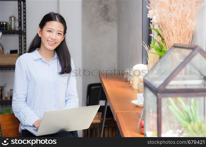 Beautiful asian young woman working online on laptop sitting at coffee shop, professional female freelancer using notebook computer with connect to internet for distance job.