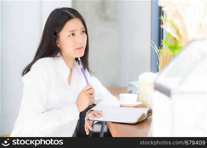Beautiful asian young woman working online with laptop and think project for idea at modern cafe shop, business and freelance concept.