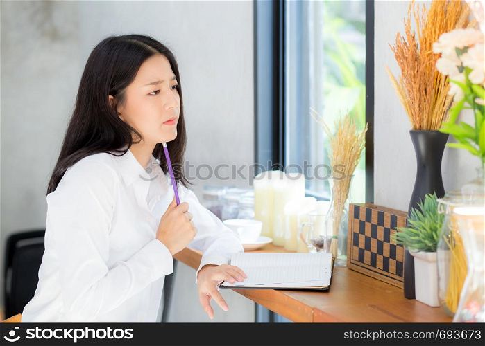 Beautiful asian young woman working online with laptop and think project for idea at modern cafe shop, business and freelance concept.