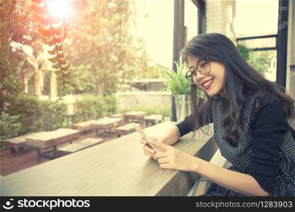 beautiful asian younger woman laughing with happiness emotion reading smart phone