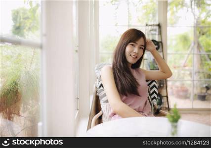 beautiful asian younger woman smiling with happiness and relaxing in home living room