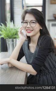 beautiful asian younger woman talking on smart phone with toothy smiling face at home