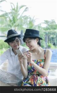 beautiful asian younger woman toothy smiling face and playing on smart phone screen