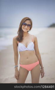 beautiful asian younger woman wearing bikini on sea beach with smiling face