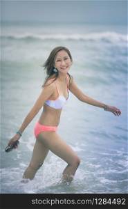 beautiful asian younger woman wearing bikini on sea beach with smiling face