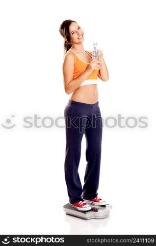 Beautiful athletic girl over a scale, isolated on white