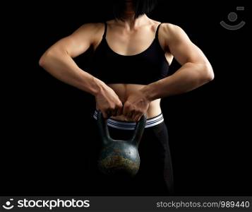 beautiful athletic girl with black hair raised with two hands a metal weight on a dark background, strength exercises, low key