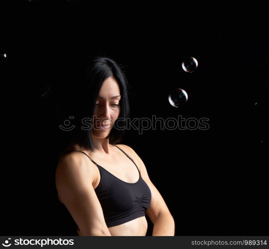 beautiful athletic woman with muscular body dressed with a black topic, sad woman face