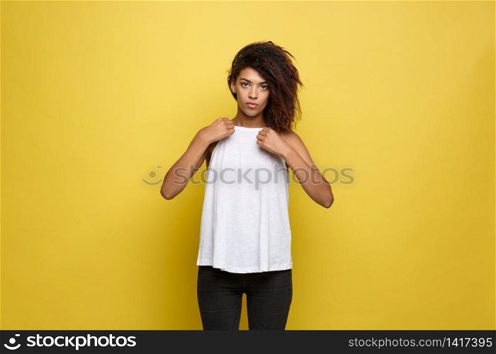 Beautiful attractive African American woman posting and dressed up her white t-shirt. Yellow studio background. Copy Space.. Beautiful attractive African American woman posting and dressed up her white t-shirt. Yellow studio background. Copy Space
