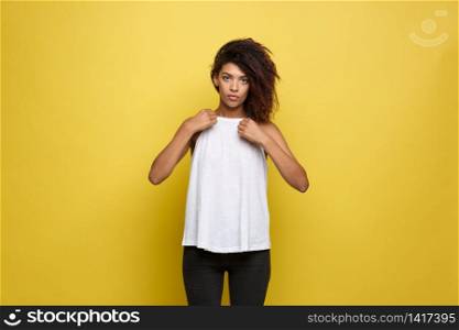 Beautiful attractive African American woman posting and dressed up her white t-shirt. Yellow studio background. Copy Space.. Beautiful attractive African American woman posting and dressed up her white t-shirt. Yellow studio background. Copy Space