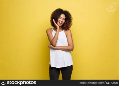 Beautiful attractive African American woman posting hold hand on her chin. Yellow studio background. Copy Space.. Beautiful attractive African American woman posting hold hand on her chin. Yellow studio background. Copy Space