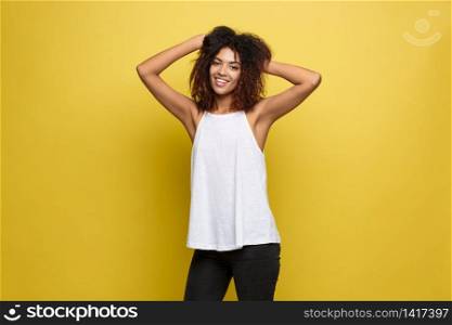 Beautiful attractive African American woman posting play with her curly afro hair. Yellow studio background. Copy Space. Beautiful attractive African American woman posting play with her curly afro hair. Yellow studio background. Copy Space.