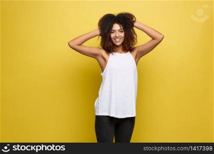 Beautiful attractive African American woman posting play with her curly afro hair. Yellow studio background. Copy Space. Beautiful attractive African American woman posting play with her curly afro hair. Yellow studio background. Copy Space.