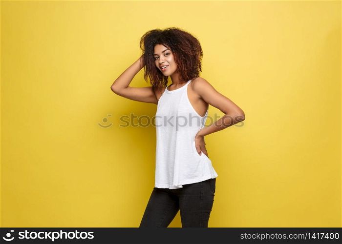 Beautiful attractive African American woman posting play with her curly afro hair. Yellow studio background. Copy Space.. Beautiful attractive African American woman posting play with her curly afro hair. Yellow studio background. Copy Space
