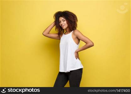 Beautiful attractive African American woman posting play with her curly afro hair. Yellow studio background. Copy Space.. Beautiful attractive African American woman posting play with her curly afro hair. Yellow studio background. Copy Space