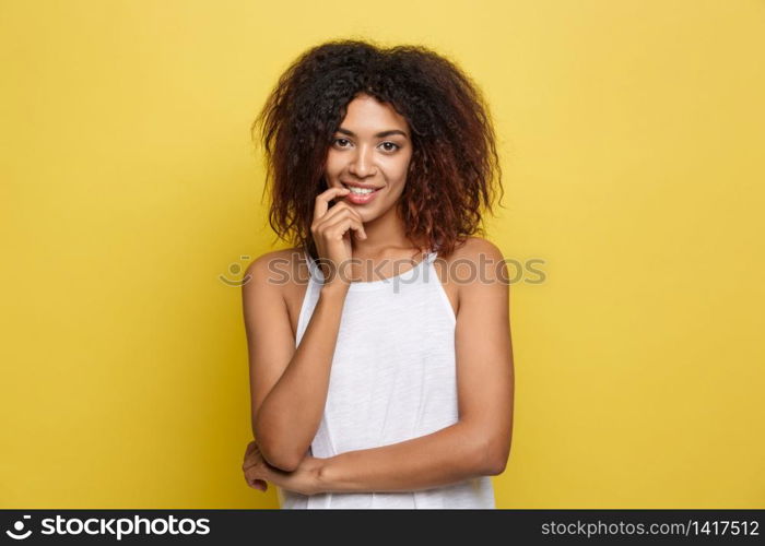 Beautiful attractive African American woman with curly afro hair thinking of something. Yellow studio background. Copy Space. Beautiful attractive African American woman with curly afro hair thinking of something. Yellow studio background. Copy Space.