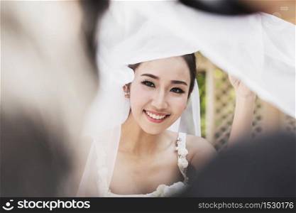 Beautiful Attractive Asian bride wearing white wedding dress and veils smile and looking feeling so proud and happiness in wedding day