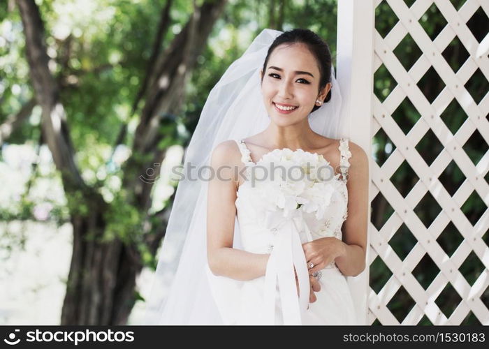 Beautiful Attractive Asian Bride Woman wearing wedding dress and holding bouquet smile and happiness in wedding day