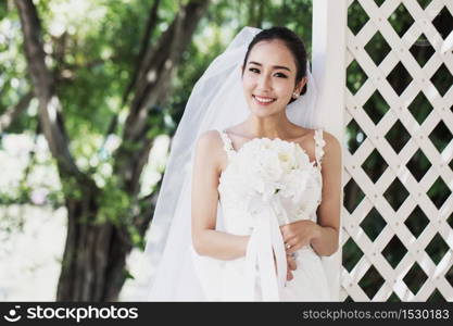 Beautiful Attractive Asian Bride Woman wearing wedding dress and holding bouquet smile and happiness in wedding day