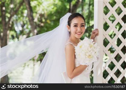 Beautiful Attractive Asian Bride Woman wearing wedding dress and holding bouquet smile and happiness in wedding day