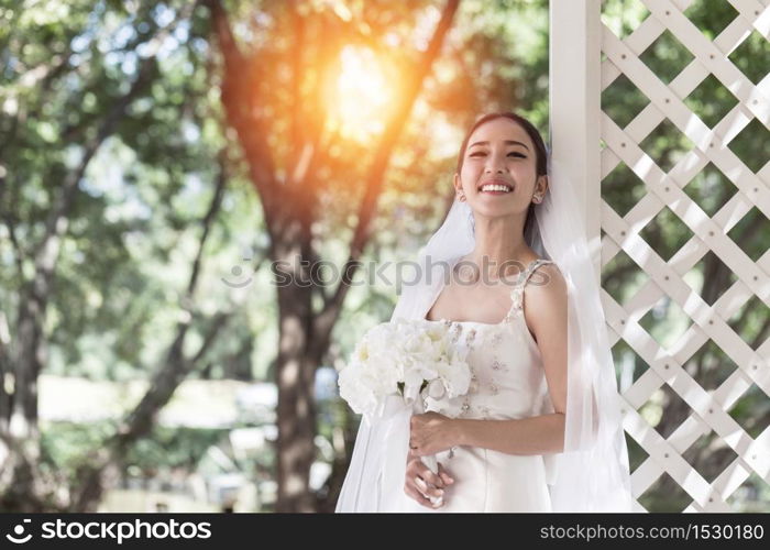 Beautiful Attractive Asian Bride Woman wearing white wedding dress and holding bouquet smile so proud and happiness in wedding day,Bride Concept