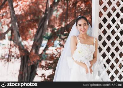 Beautiful Attractive Asian Bride Woman wearing white wedding dress and holding bouquet smile so proud and happiness in wedding day,Bride Concept