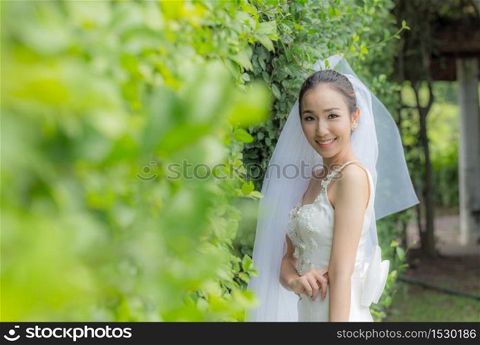 Beautiful Attractive Asian Bride Woman wearing white wedding dress and holding bouquet smile so proud and happiness in wedding day,Bride Concept
