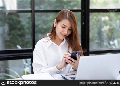 Beautiful Attractive Asian business woman holding smartphone for using social media in coffee shop cafe smile and happiness