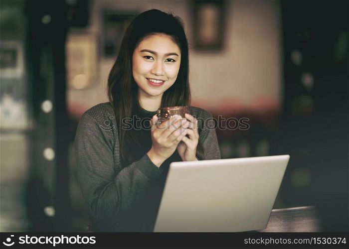 Beautiful Attractive Asian Business woman smile and holding coffee in Coffee shop cafe with computer laptop on the table feeling so happiness and comfortable,Vintage Tone