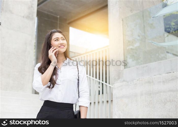 Beautiful Attractive Asian Business woman smile talking with customer in smartphone outside office to get requirement with her job feeling so happiness and confident,Business Concept