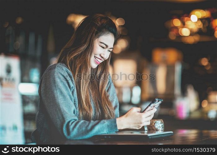 Beautiful Attractive Asian business woman using smartphone in coffee shop cafe smile and happiness,Warm Tone
