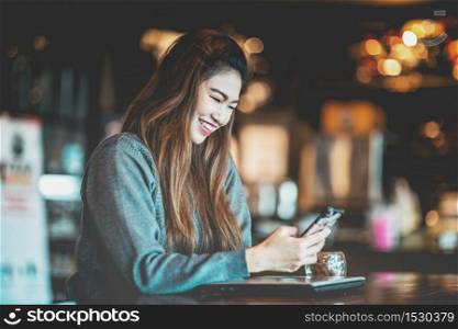 Beautiful Attractive Asian business woman using smartphone in coffee shop cafe smile and happiness,Warm Tone