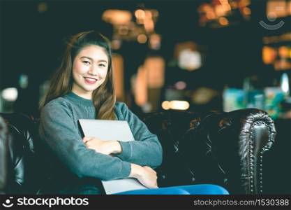 Beautiful Attractive Asian Business woman wearing sweater smile and hug computer laptop on sofa in coffee shop cafe feeling so happiness and comfortable,Vintage tone,Business Startup Concept