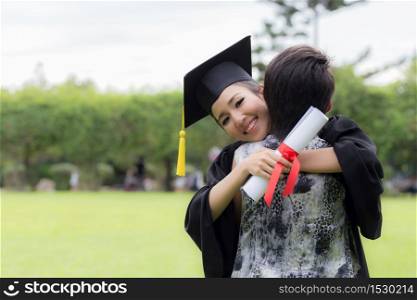 Beautiful Attractive Asian graduate woman in cap and gown celebrating hug with parent feeling so proud and happiness on Commencement day,Graduation Education Success Concept