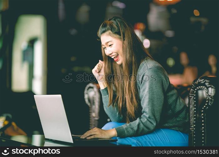 Beautiful Attractive Asian woman celebrating with laptop after success job feeling so happy and cheerful,Business Startup concept
